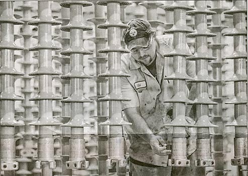 Group leader Ed Hodgdon of Warsaw stamps line posts at Lapp Insulators in Le Roy on Friday.