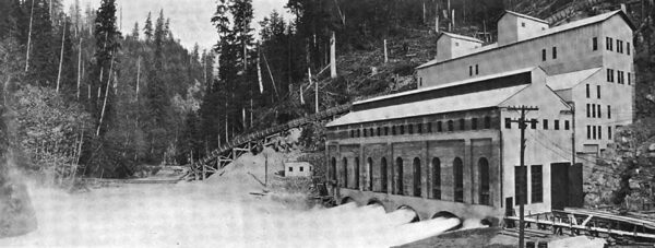 WEST SIDE OF THE POWER HOUSE. SHOWING FOUR GENERATORS IN OPERATON: ALSO THE TEMPORARY WALL AND GRADING AND TRENCHING TO THE RIGHT TO FACILITATE THE INSTALLATION OF THE FOUR ADDITIONAL PENSTOCKS AND GENERATORS.