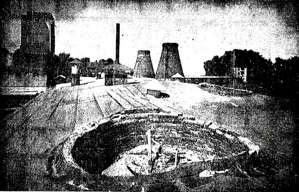 In the background of this roof view are two conical chimneys that once belched flame 40 feet high to make porcelain in big beehive ovens.  In the foreground is one partly dismantled with a draft control in the center.  Oven temperature used to be gauged by noting the color of flame over a 25 to 65-hours period.  If heat varied more than 20 degrees, the "charge" (load of porcelain products being processed in the kilns) would be spoiled.  This plant, owned by the Hartford Faience Corporation, once operated 10 kilns.  Old giant hand-fed, coal-burning oven had been in use since 1894 when the firm was established.