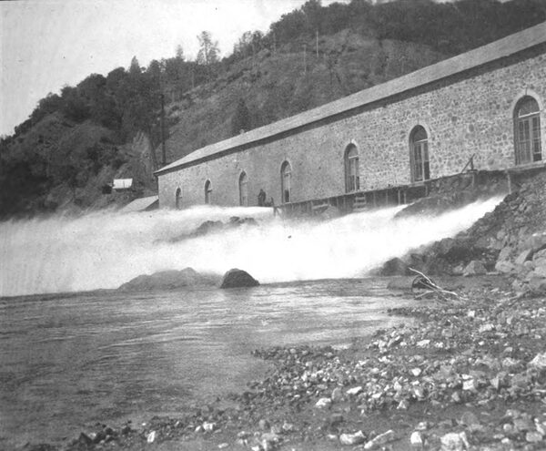 AT THE COLGATE POWER HOUSE. � AT TIMES OF LIGHT LOAD PORTIONS OF THE STREAM SHOOT OUT INTO THE RIVER WITHOUT STRIKING THE IMPULSE WHEELS. NO ATTEMPT IS MADE TO �CONTROL\" THE FLOW OF WATER BY THE GOVERNING APPARATU