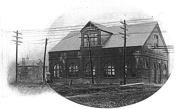 FIG. 1. � THE EXTERIOR OF THE TRANSFORMING STATION OF THE TONAWANDA POWER COMPANY/The six upper wires on the poles in the foreground are the two three-phase lines running from Niagara on the right toward Buffalo on the left. Taps from these pass into the left-hand side of the gable. The lower three wires passing out to the right form the 11,000-volt branch line to Lockport. The heavy wires passing out from the right-hand end of the building are the railway feeders, and the lighter wires beyond them are the central station lines.
